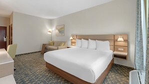 Une chambre d’hôtel avec un grand lit, un bureau, une chaise et une table de chevet avec des lampes.