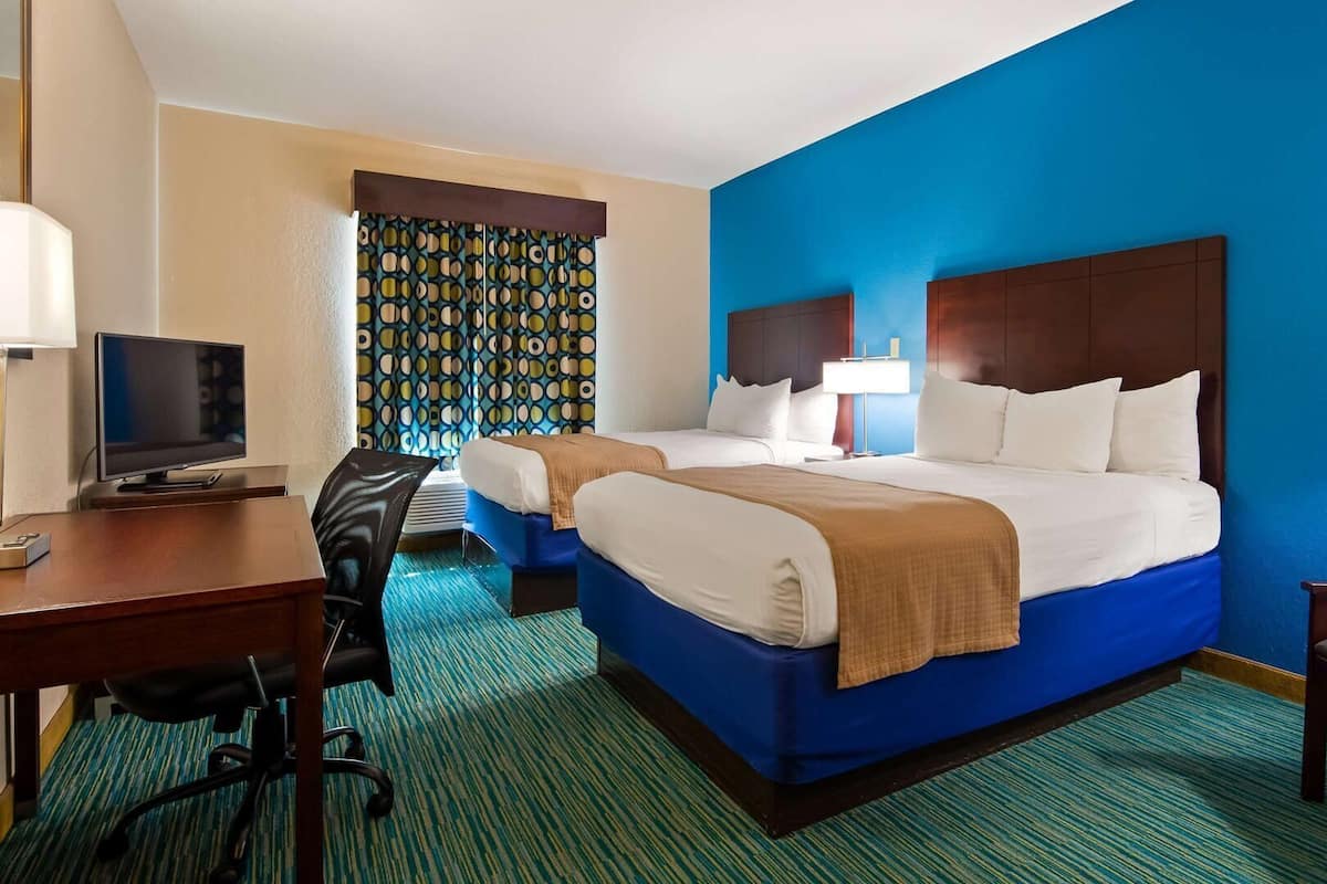 Une chambre d’hôtel avec deux lits, un bureau, une télévision et une chaise.