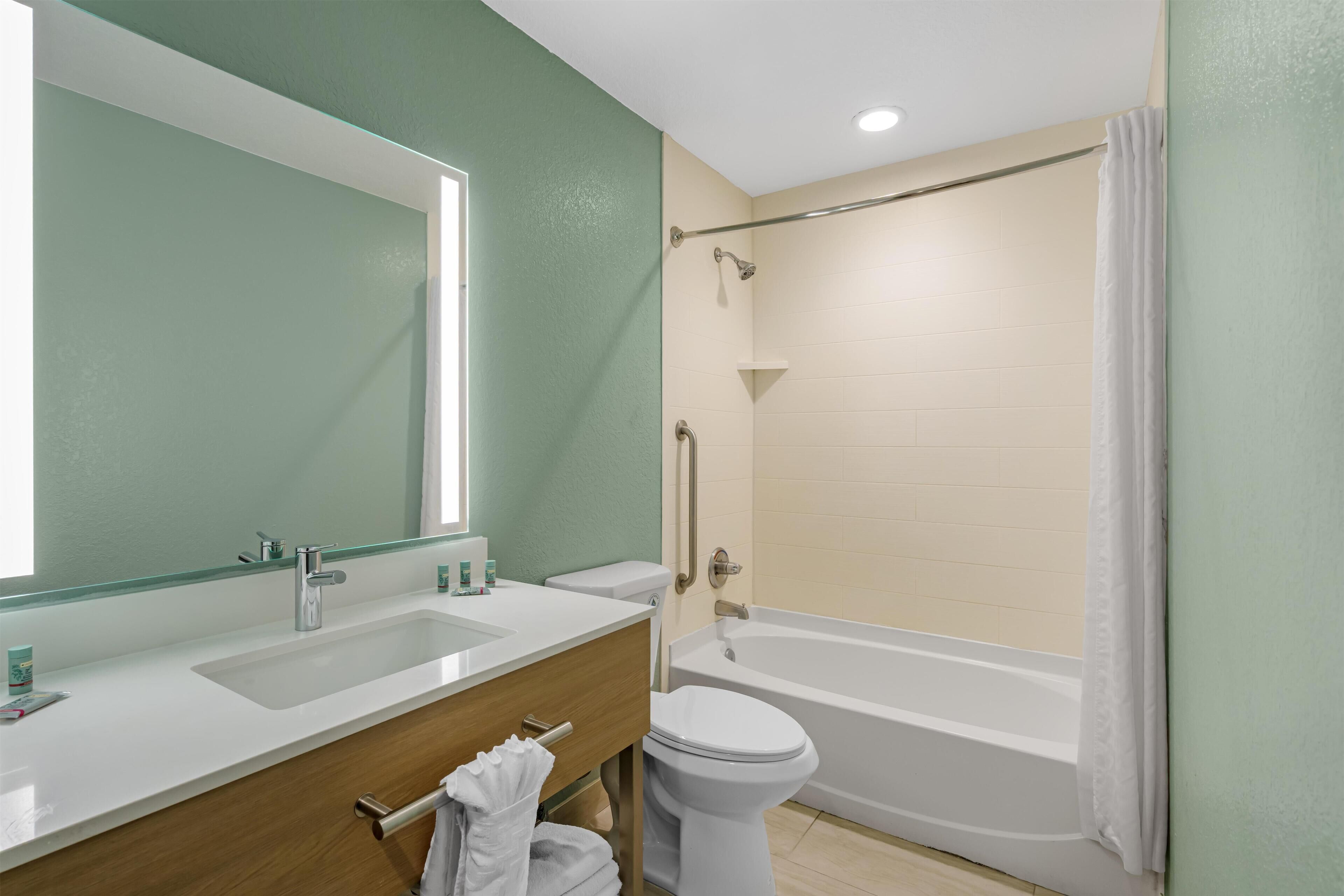 A bathroom with a sink, mirror, toilet, and bathtub.