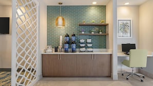 Un espace d’accueil moderne avec un mur recouvert de carreaux turquoise, un comptoir en bois et un fauteuil de bureau vert.