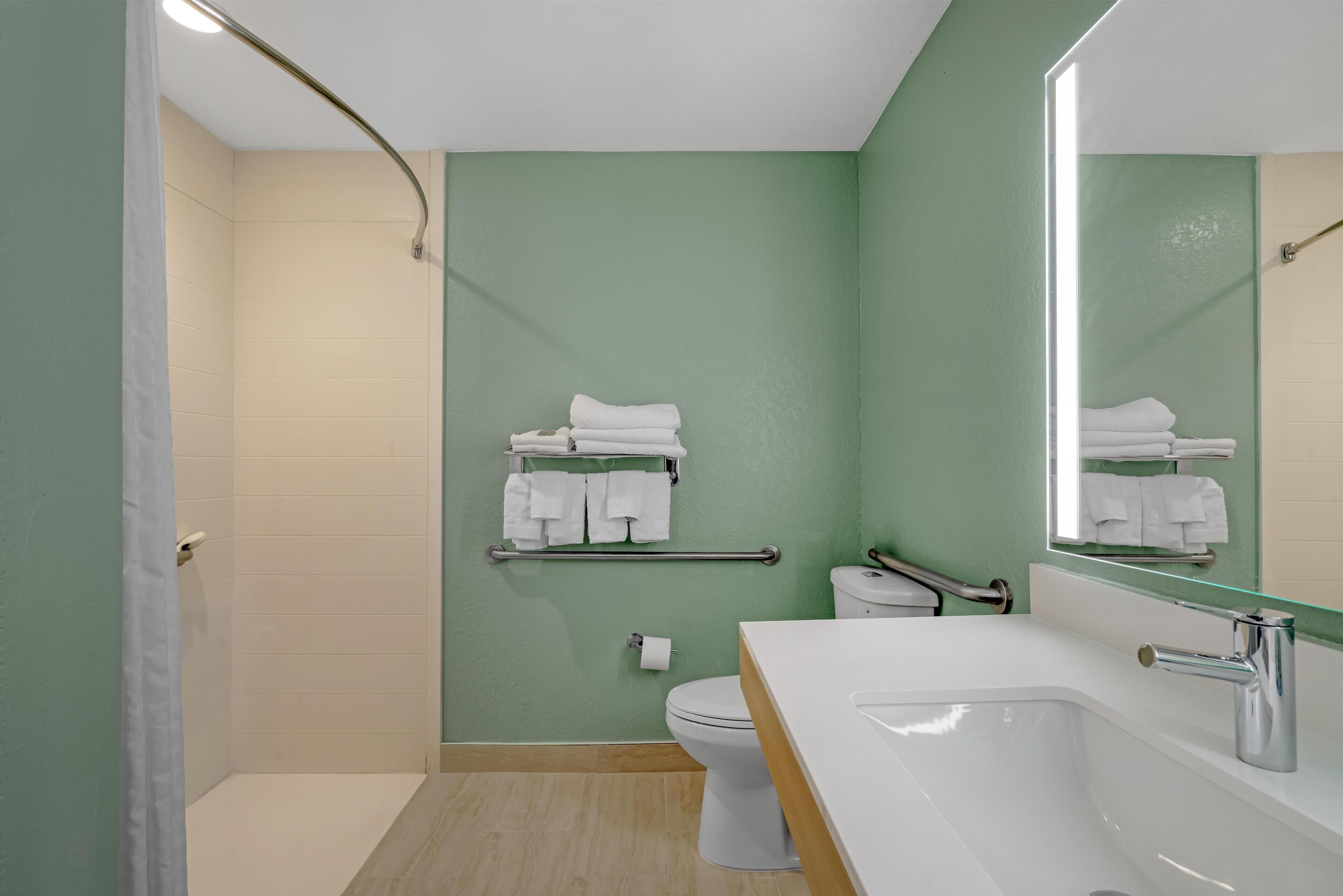A modern bathroom with a shower, toilet, and sink.