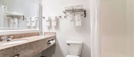 A modern bathroom with a sink, mirror, toilet, and towel rack.