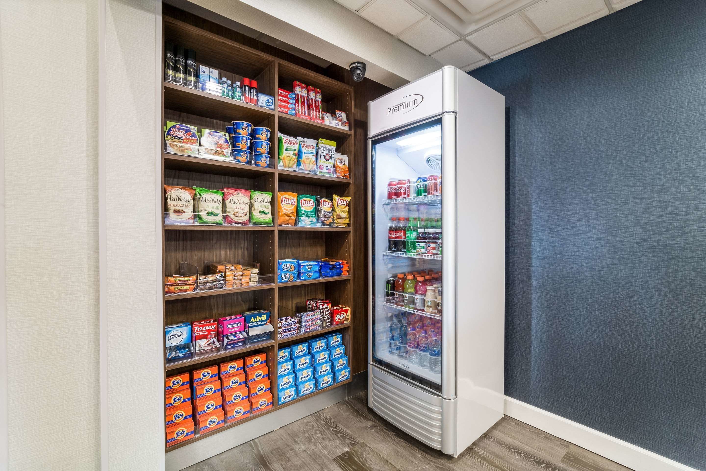 A refrigerated display case stocked with beverages and a shelf unit with various food products.