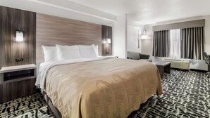 A hotel room with a large bed, bedside tables, a desk, and a chair.