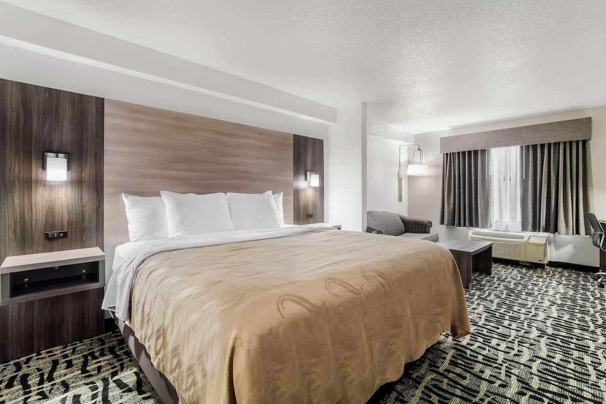 Une chambre d’hôtel avec un grand lit, des tables de chevet, un bureau et une chaise.