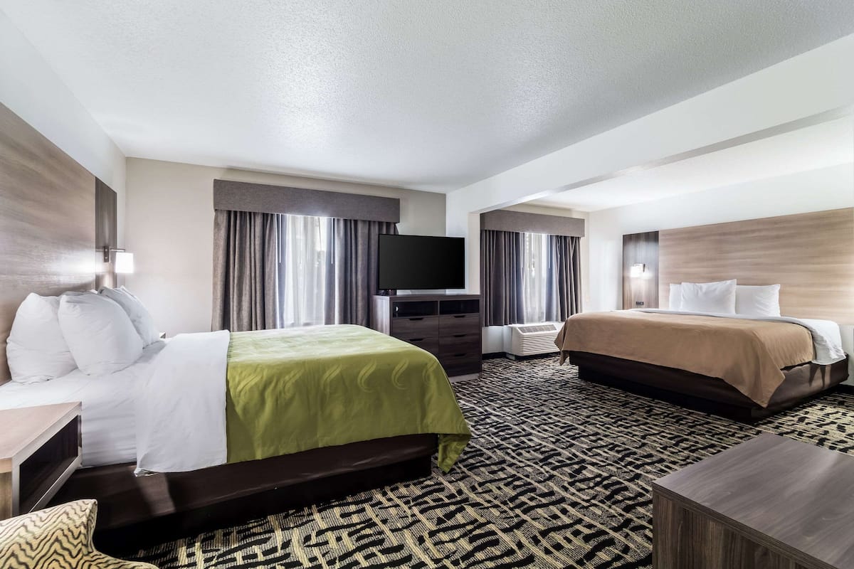 Une chambre d’hôtel avec un lit, une télévision, une commode et un sol recouvert de moquette.