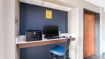 Un espace de travail comprenant un bureau, deux ordinateurs portables, une imprimante et une chaise bleue.