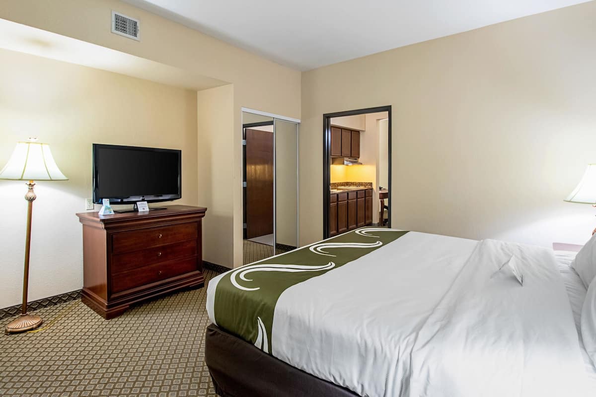 A hotel room with a bed, a dresser, a television, and a mirror.