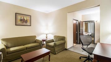 Une chambre d’hôtel avec un canapé vert, une petite table, une lampe, une chaise et un bureau.