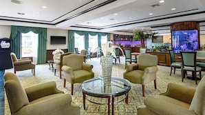 A hotel lobby with a seating area, a reception desk, a large aquarium, and a television.