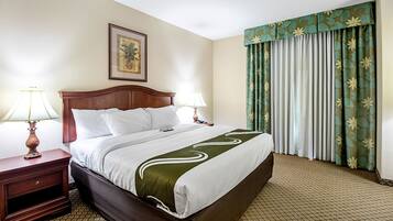 Habitación de hotel con una cama grande, dos mesitas de noche con lámparas, un cuadro en la pared y una ventana con cortinas.