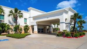 A hotel entrance with a covered walkway, palm trees, and a wheelchair-accessible ramp.