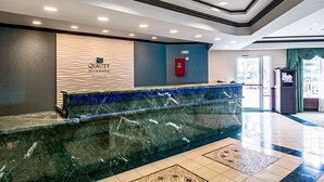 A reception area with a marble counter, a wall-mounted logo, and a fire alarm.
