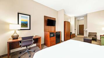 Habitación de hotel con cama, escritorio, silla, armario, televisión y un cuadro en la pared.
