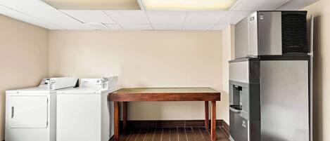 Una cocina compacta con lavadora, una mesa y un refrigerador.