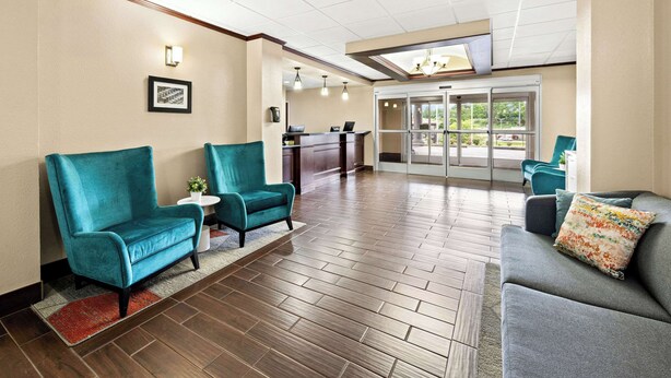 A lobby with teal and gray sofas, a reception desk, and a view through a glass door.