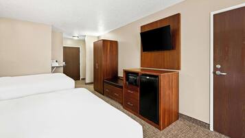 A hotel room with two beds, a wooden wardrobe, a flat-screen TV, and a door.