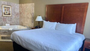 A hotel room with a large bed, a separate shower area, a bathtub, and a wooden headboard. - Best Western Emporia Inn (Emporia)