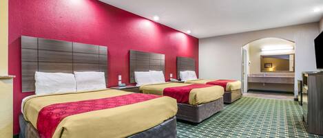 A hotel room with two beds, a green patterned carpet, and a red accent wall.