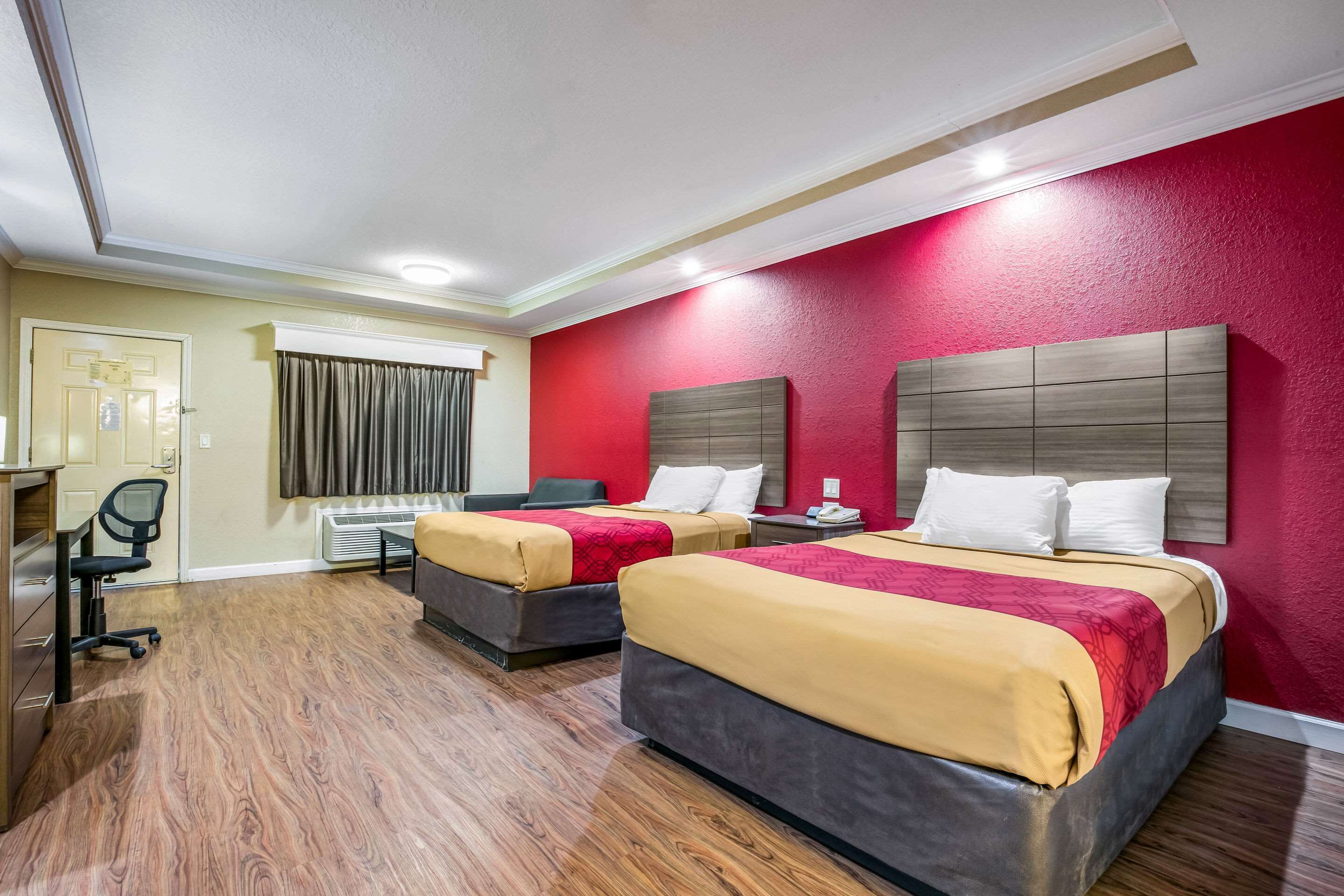 A hotel room with two beds, a desk, and a chair.