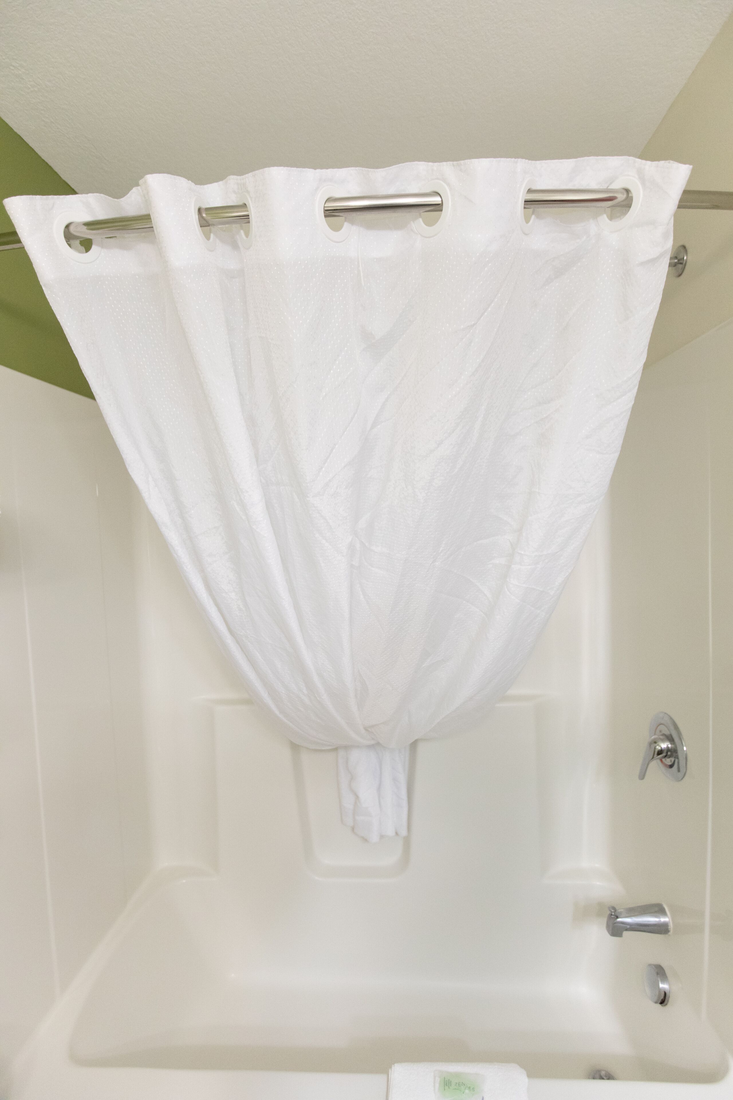 Un baño con una bañera blanca, una cortina de ducha y un perchero para toallas.