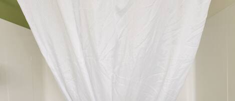 A bathroom with a white bathtub, a shower curtain, and a towel rack.