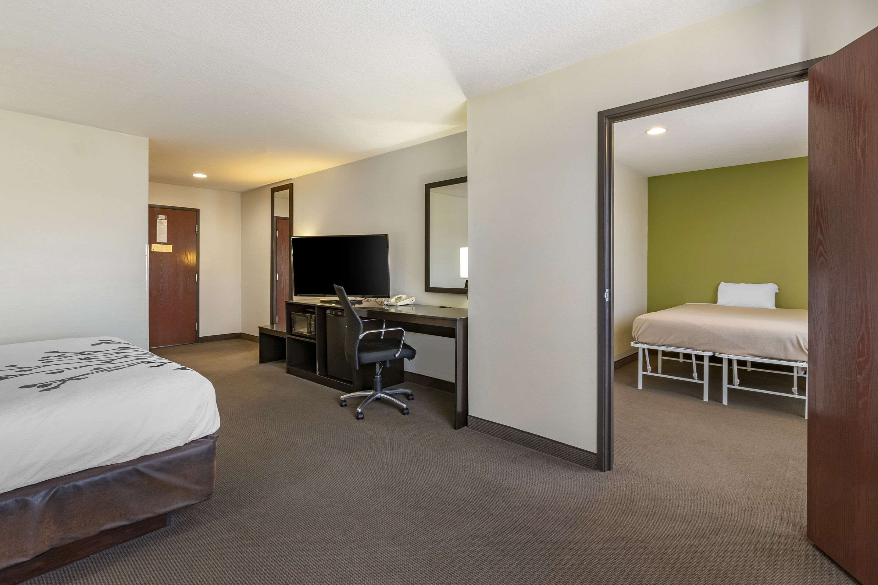 A hotel room with a bed, desk, chair, and a television.