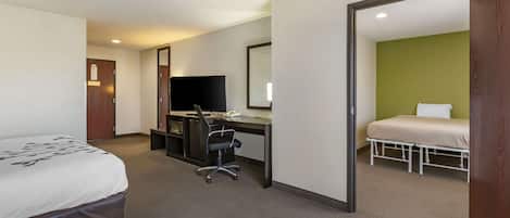A hotel room with a bed, desk, chair, and a television.