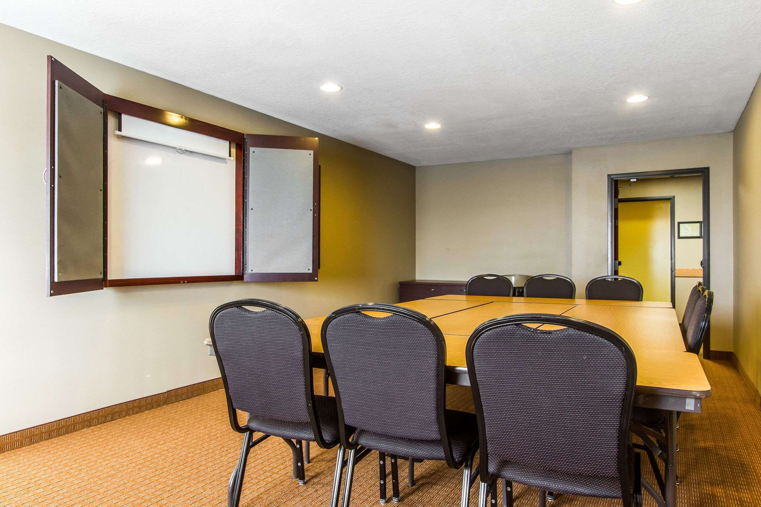 A conference room with a large table, four chairs, and two whiteboards on the walls.