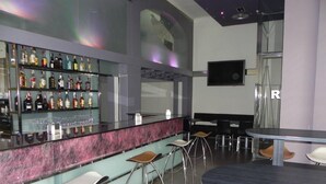 Een bar met een marmeren aanrecht, verschillende krukken en een selectie drankflessen.