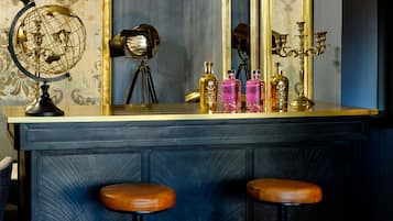 A bar area with two stools, a globe lamp, and a mirror with a candelabra.