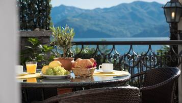 A table with breakfast items, a potted plant, and a view of mountains.
