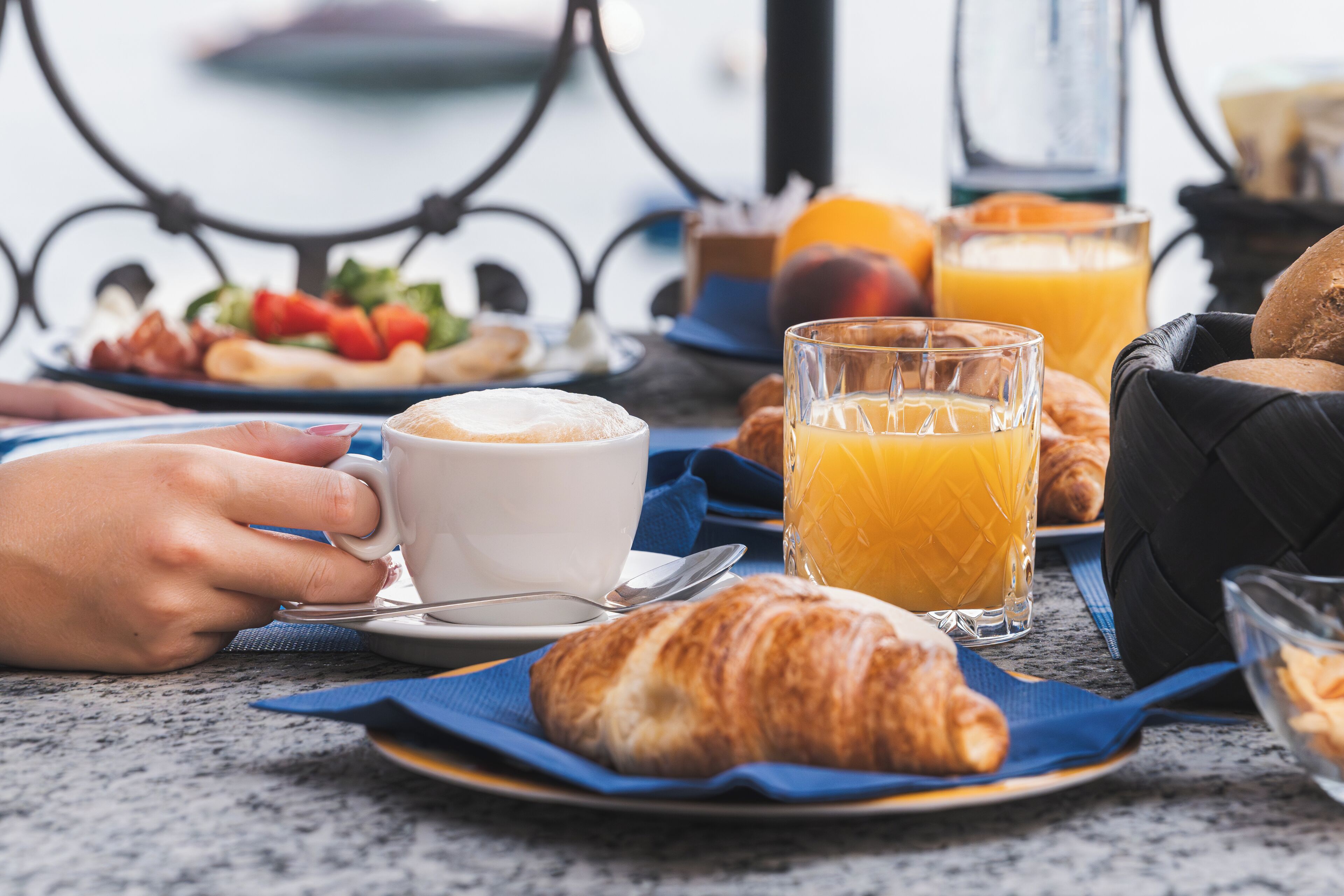 Desayuno con croissants, jugo de naranja y una taza de café sobre una mesa.
