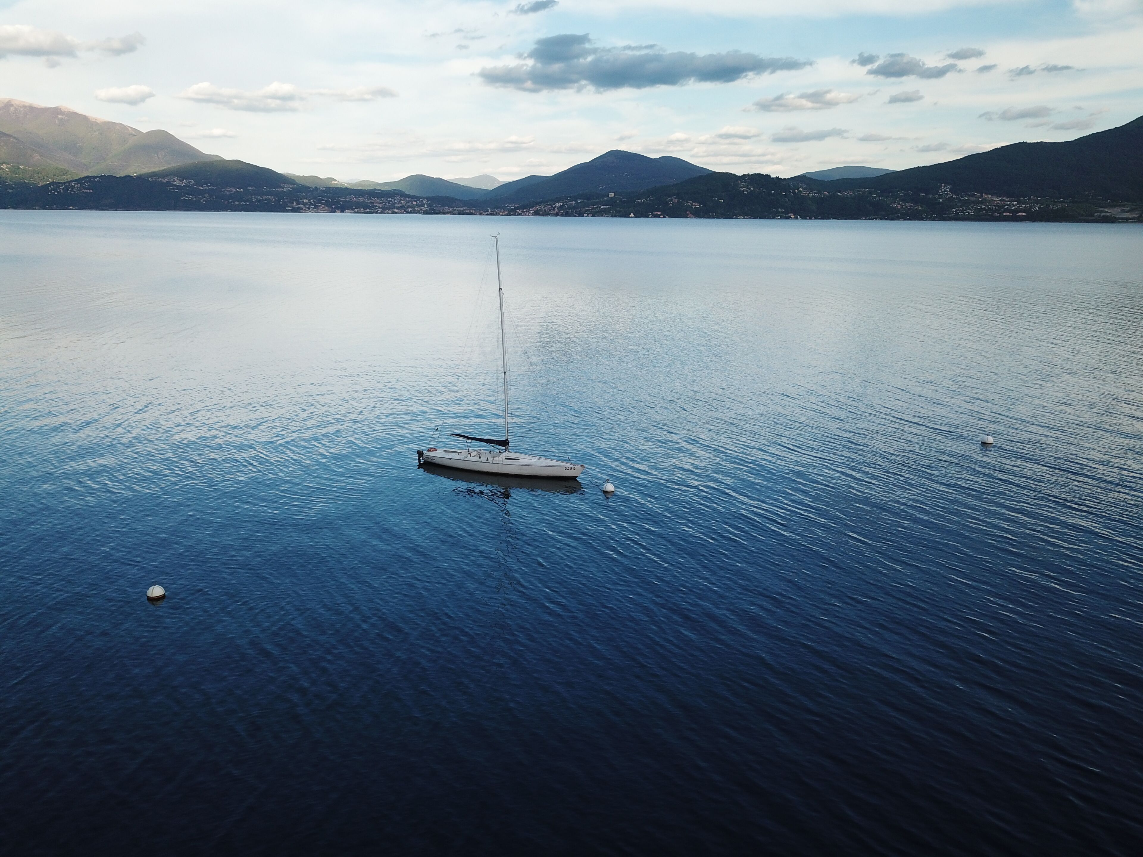 A calm lake with a small boat anchored in the center, surrounded by mountains and a clear sky.
