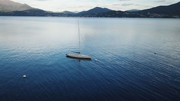 A calm lake with a small boat anchored in the center, surrounded by mountains and a clear sky.