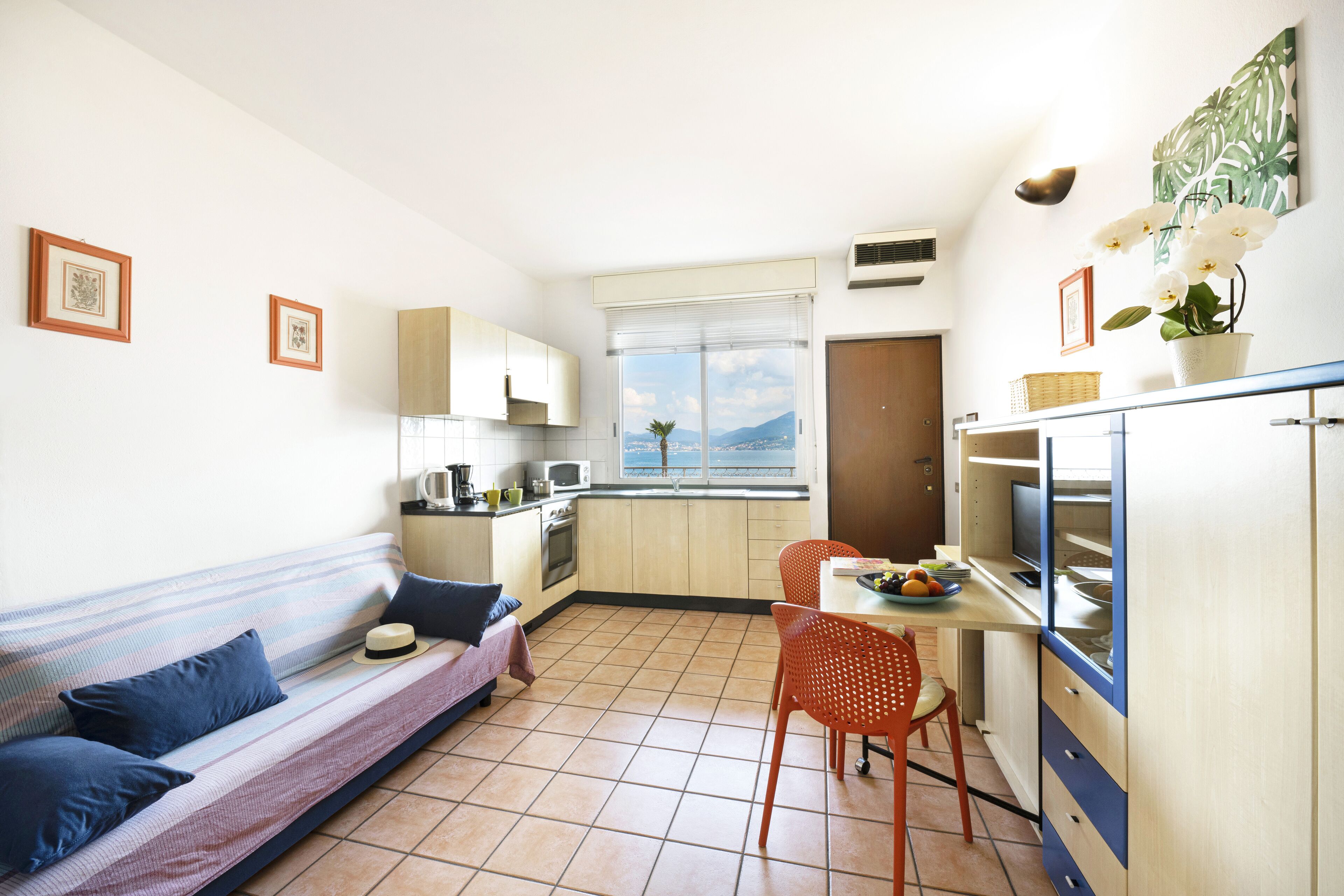 A compact kitchen with a dining area, a sofa, and a window with a view.