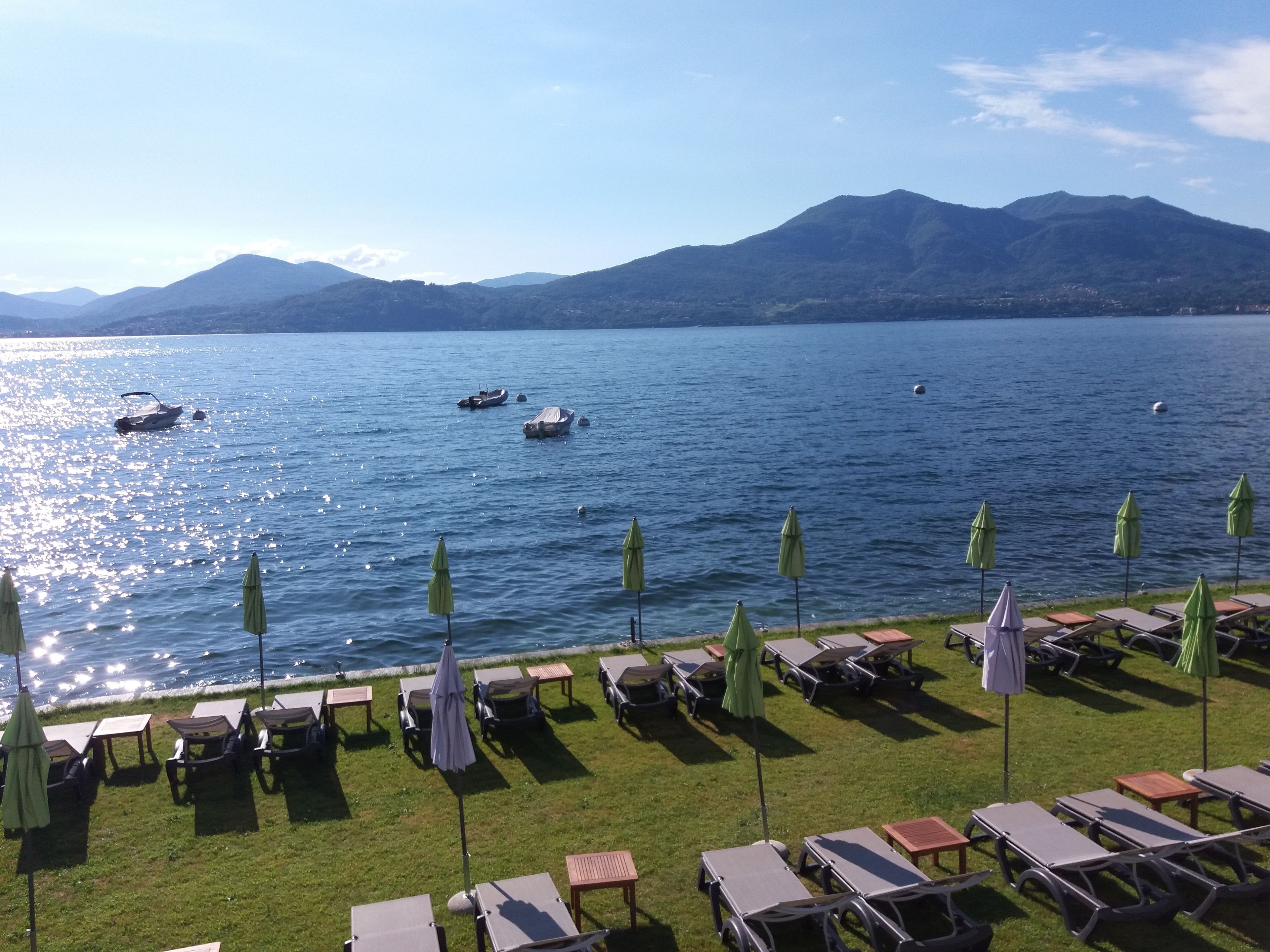 A lakeside view with boats, umbrellas, and lounge chairs.