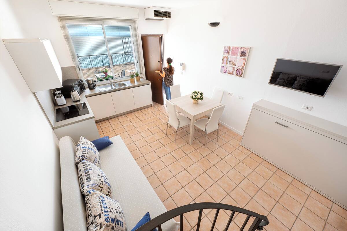 Een knus woongedeelte met een kitchenette, een eethoek en een zithoek met een bank en stoelen.