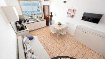 A compact living space with a kitchenette, a dining area, and a seating area with a sofa and chairs.