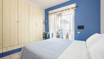 Een slaapkamer met een bed, een kledingkast, een bureau en een stoel.