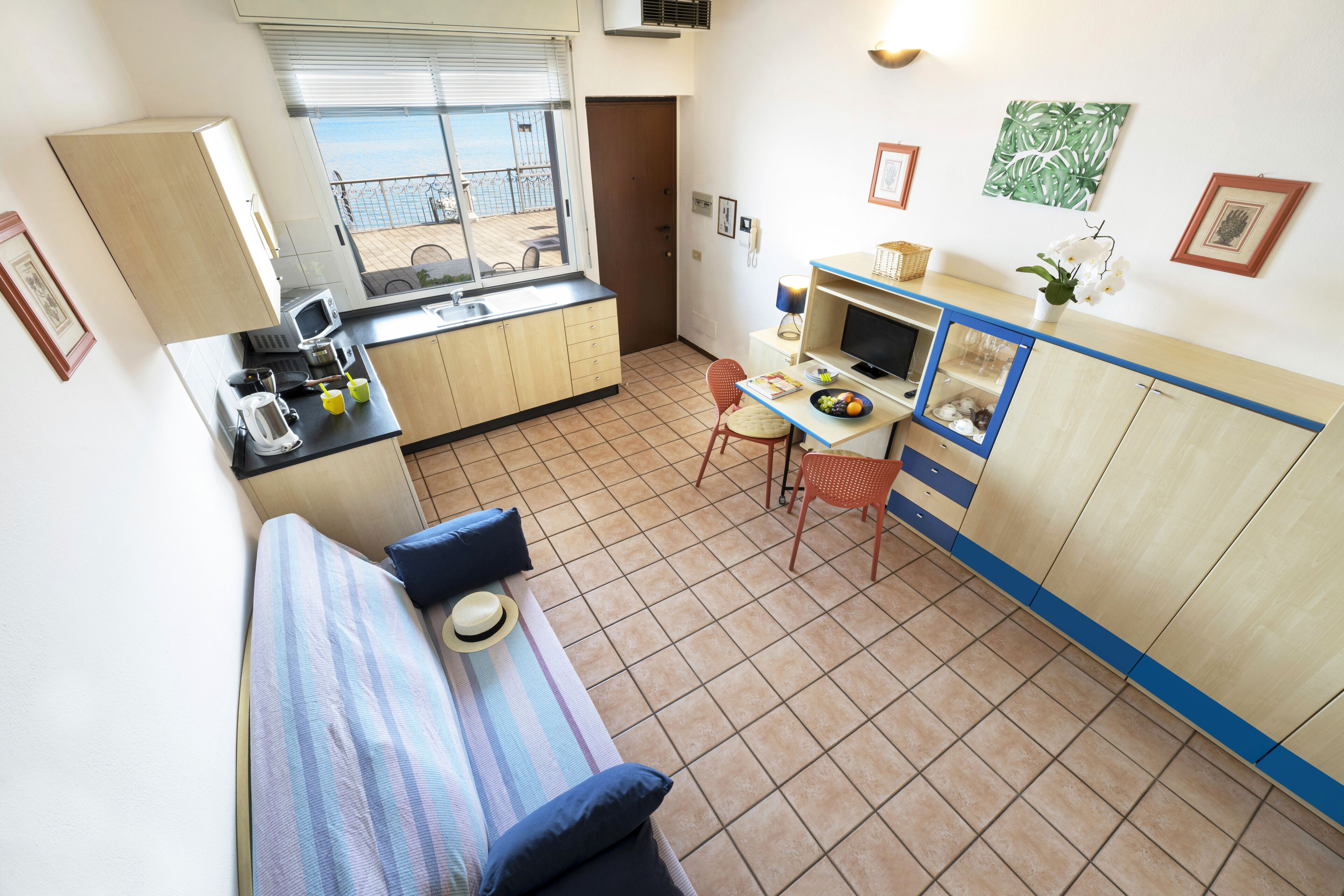 A compact room with a kitchenette, a dining area, and a bed.