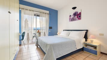 Un dormitorio con cama, mesita de noche, silla y vistas al exterior a través de una ventana.