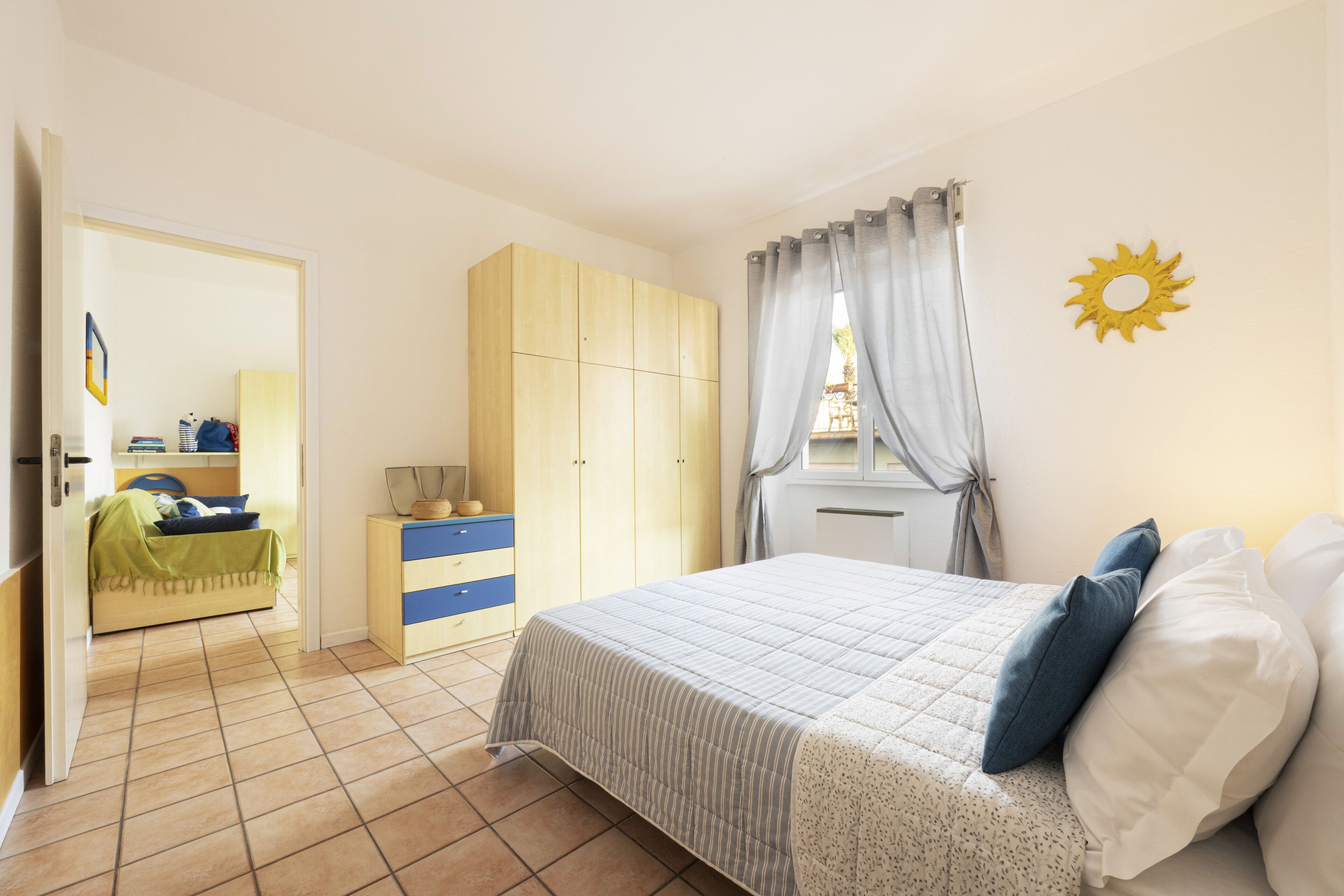 A bedroom with a bed, a wardrobe, a bedside table, and a window with curtains.