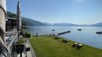 A lakeside terrace with a view of the lake, boats, and mountains.
