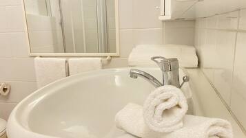 Une salle de bain avec un lavabo blanc, un miroir et une serviette.
