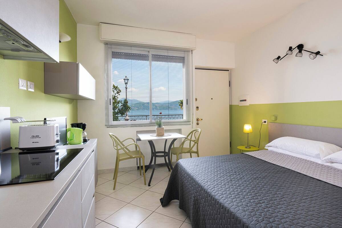 Een compacte hotelkamer met kitchenette, een eethoek, een bed en uitzicht op zee.