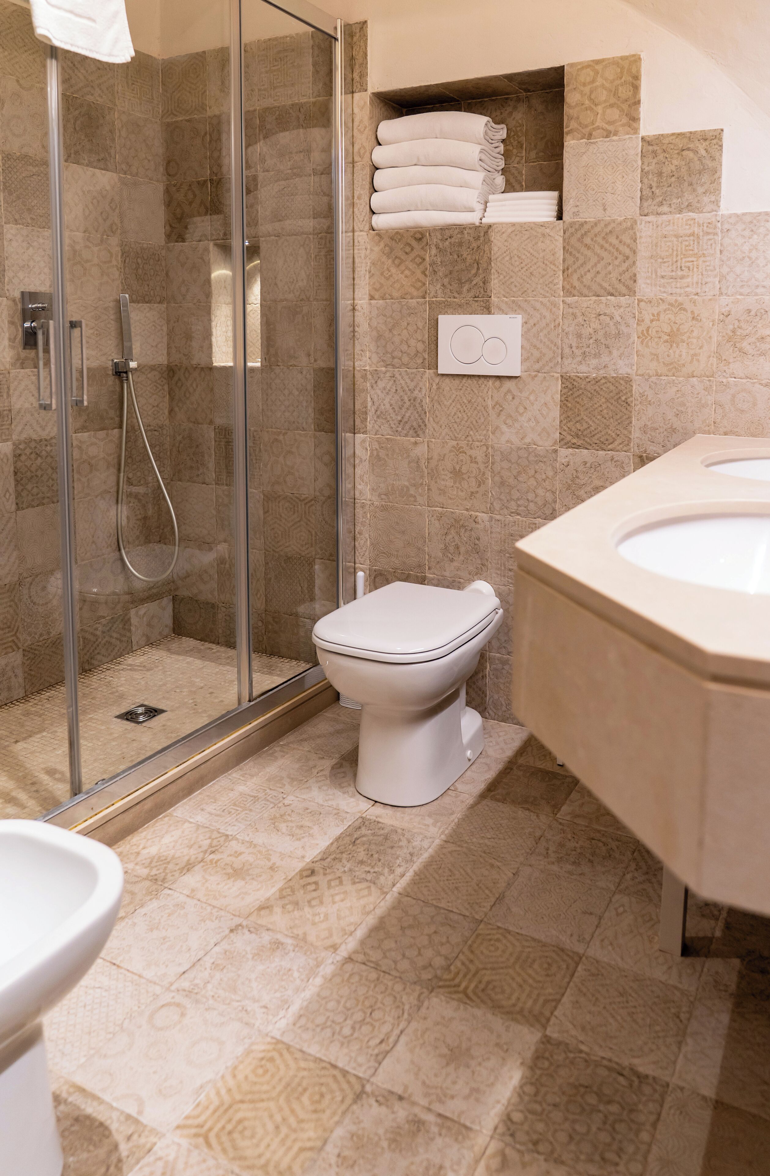 Een badkamer met een douchecabine van glas, een toilet en een wastafel.