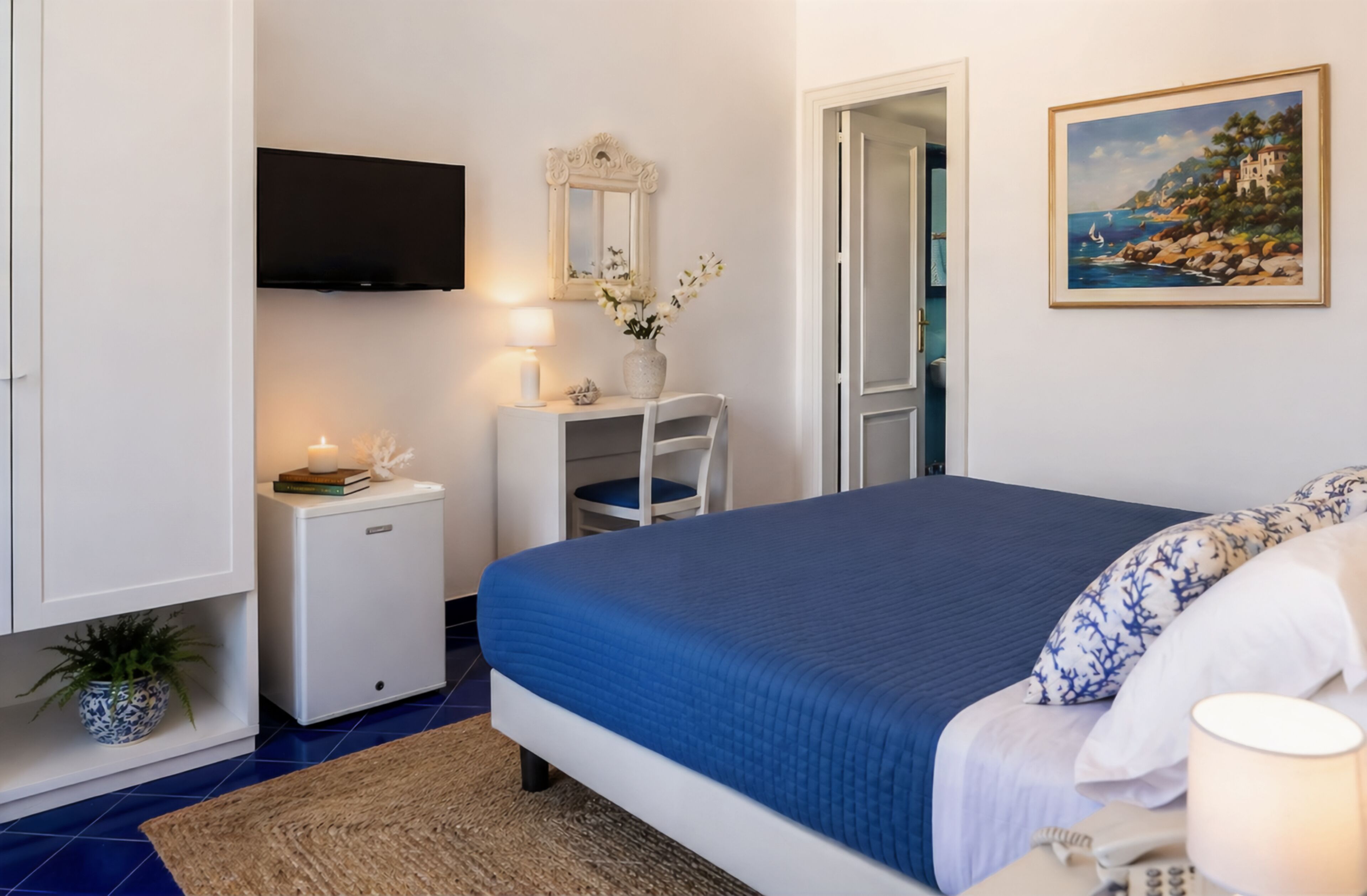 A bedroom with a bed, bedside table, lamp, TV, and a painting on the wall.