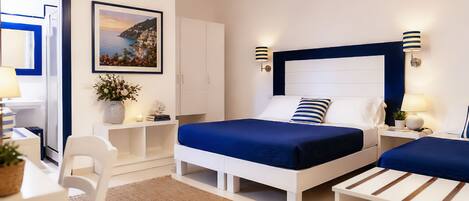 Habitación de hotel con cama, mesitas de noche, una silla, escritorio, lámpara, un cuadro en la pared y ventana.