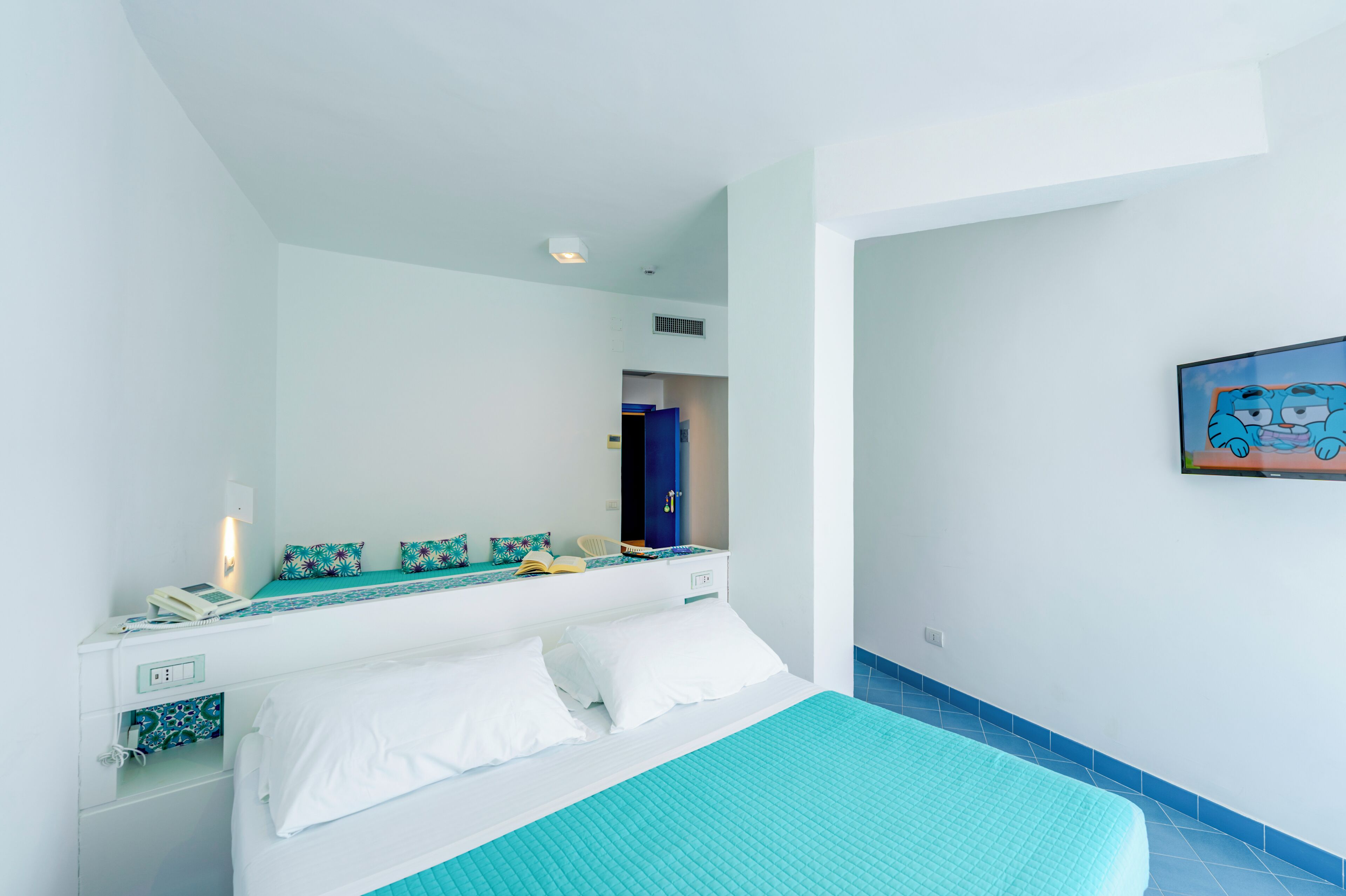 A bedroom with a bed, bedside table, and a mirror.